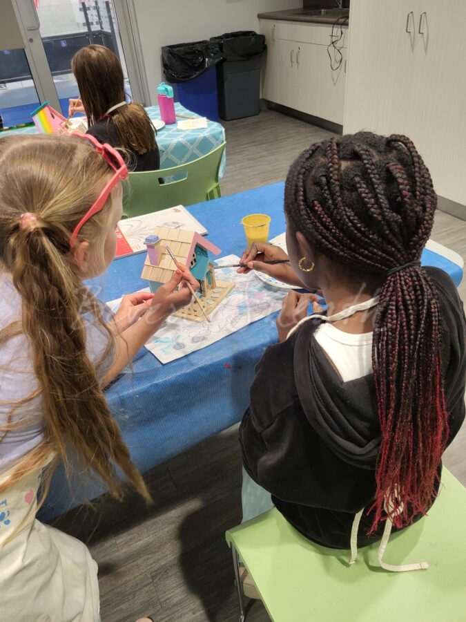 two girls painting a bird house