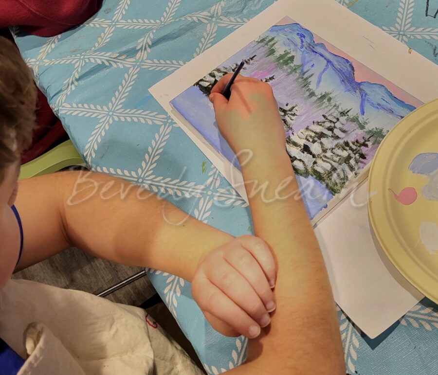 boy painting winter scene with acrylics on canvas