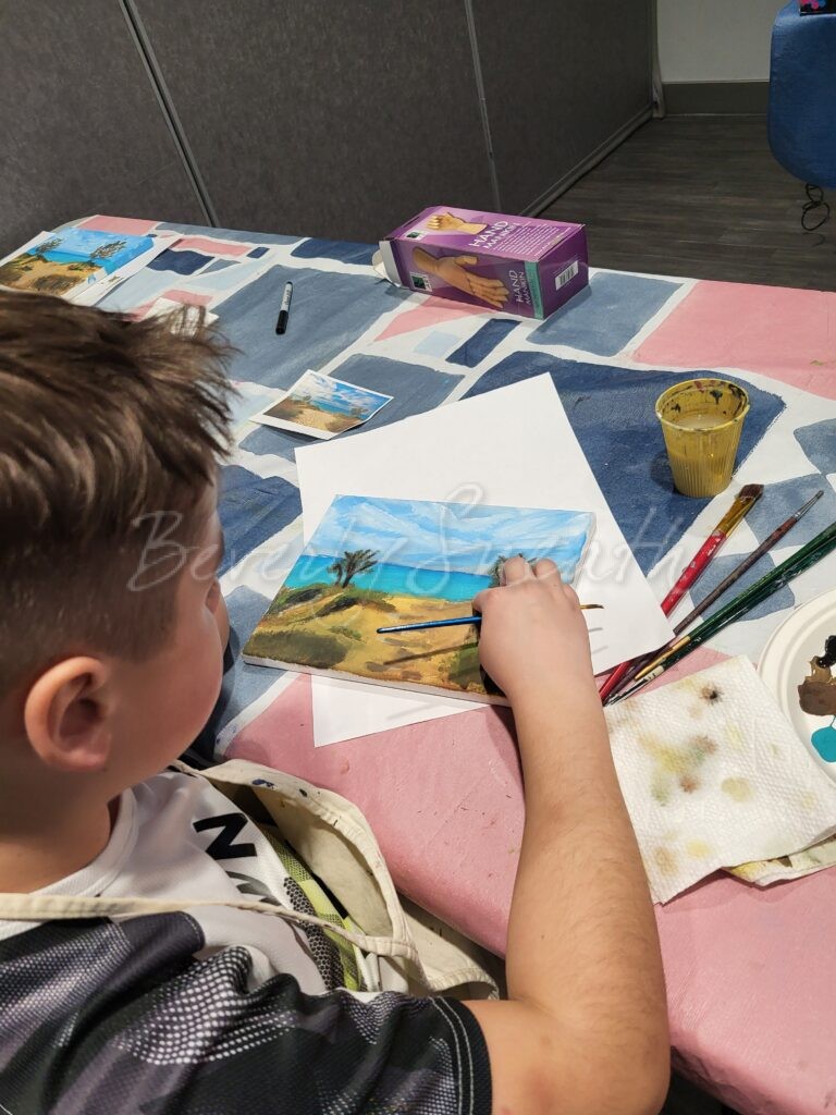 boy painting a landscape with acrylics on canvas